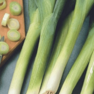 Fresh green onions on a wooden surface with sliced pieces.